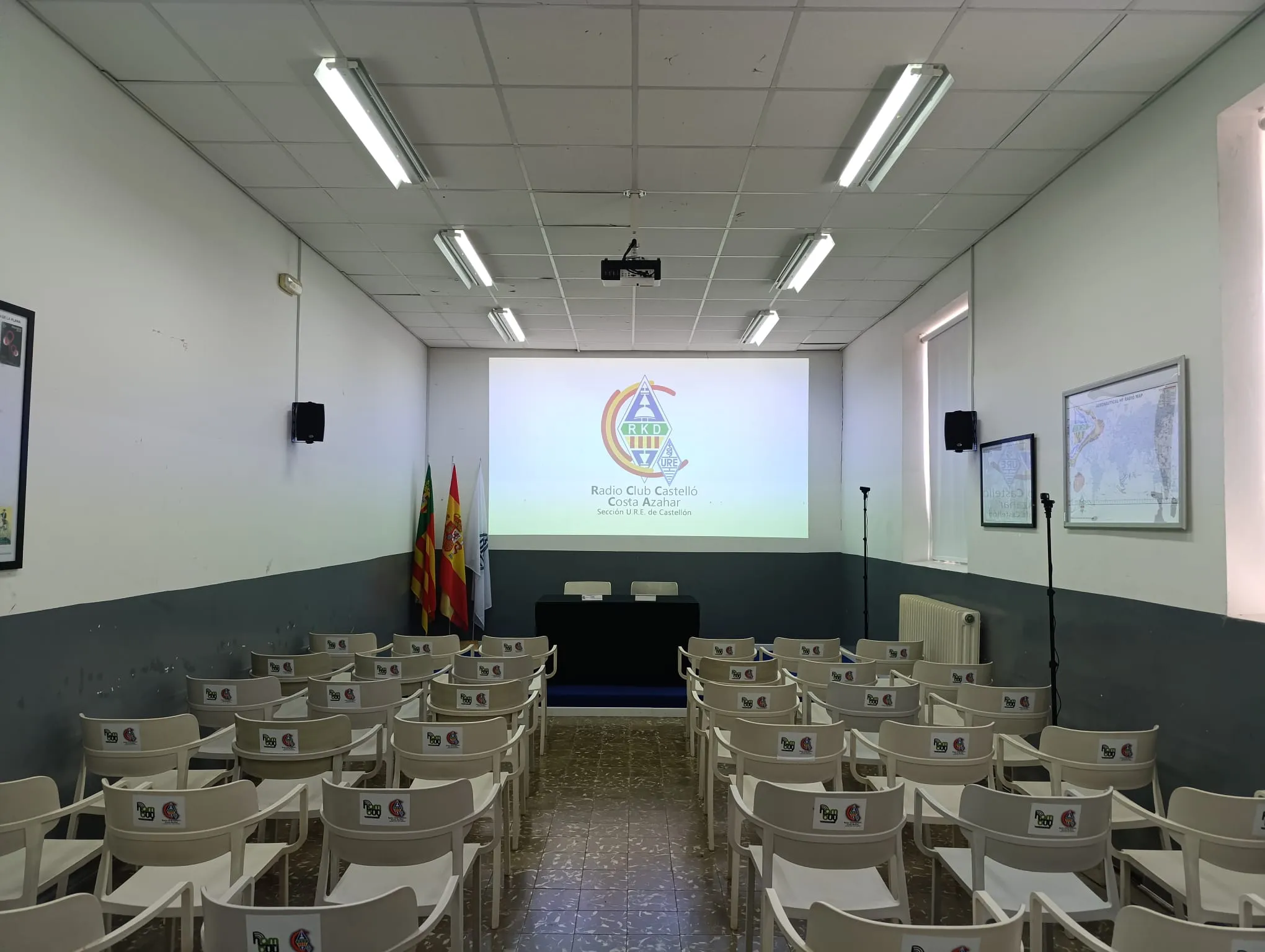 La sala de conferencias del club, con filas de sillas frente a la pantalla del proyector.
